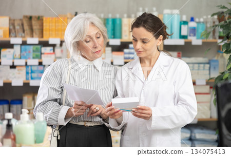 Mature woman consults pharmacist in pharmacy Mature woman consults pharmacist in pharmacy 134075413