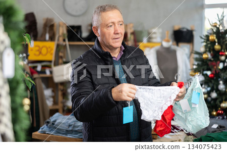 Attentive mature man choosing ladies panties in clothing store Attentive mature man choosing ladies panties in clothing store 134075423