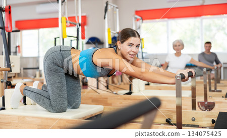 Young woman doing stretching on pilates machine Young woman doing stretching on pilates machine 134075425