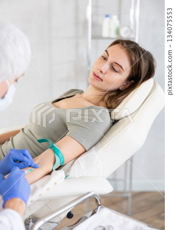 Female doctor doing injection to smiling calm young woman in clinic. Female doctor doing injection to smiling calm young woman in clinic. 134075553