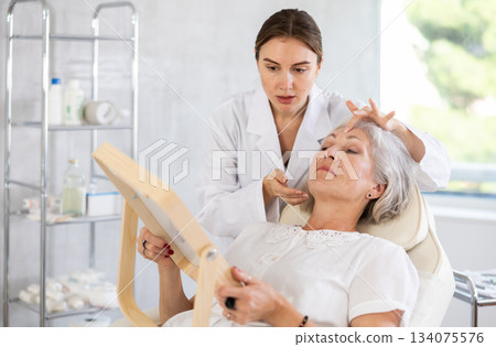 Cosmetologist with gloves preparing patient to skin care procedure in spa salon. Cosmetologist with gloves preparing patient to skin care procedure in spa salon. 134075576