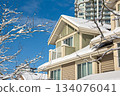 Top of residential house in snow and high-rise building on blue sky background Top of residential house in snow and high-rise building on blue sky background 134076041