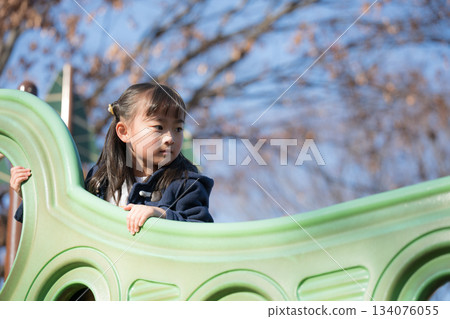 Children playing on playground equipment in an autumn park. Image of winter children's outings and leisure activities. 134076055