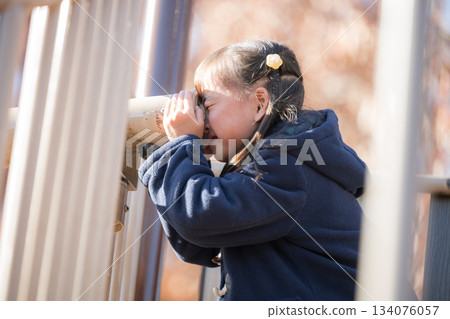 Children playing with playground equipment in an autumn park. Images of children going out and having leisure time in winter. Looking through a telescope. Children playing with playground equipment in an autumn park. Images of children going out and having leisure time in winter. Looking through a telescope. 134076057