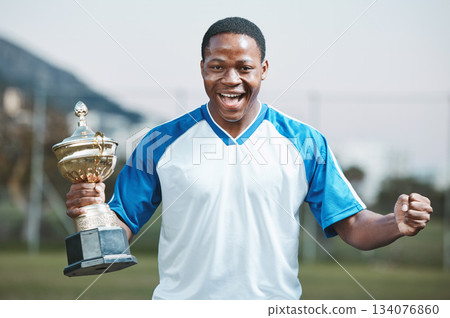 Sports, soccer player and man celebrate trophy for competition or game outdoor. Portrait of black male athlete champion excited for football prize, award and win or achievement and success on a field 134076860