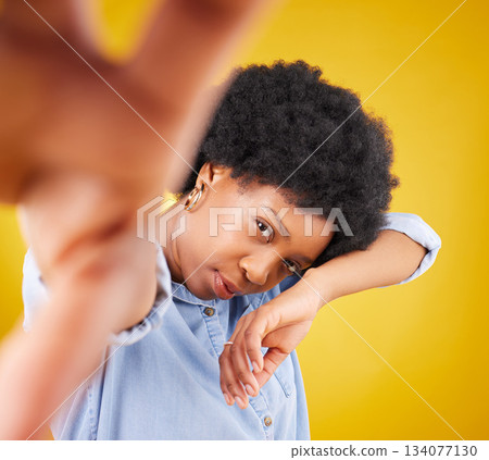 Hand, selfie and black woman in studio for fashion, creative and pose against a yellow background. Face, serious and African female influencer posing for profile picture, photo or web post isolated 134077130