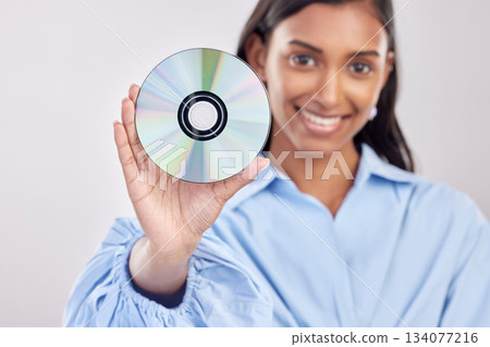 Woman, compact disk and smile in studio portrait for programming, software and information technology. Young indian girl, cd and happy with movie, music and data storage for media by white background Woman, compact disk and smile in studio portrait for programming, software and information technology. Young indian girl, cd and happy with movie, music and data storage for media by white background 134077216