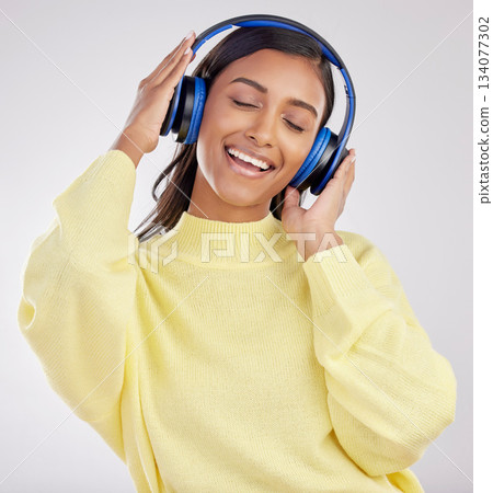 Woman with headphones, listening to music and happy on studio background with freedom, fun and peace. Smile, carefree and technology with entertainment, Indian female and radio streaming playlist Woman with headphones, listening to music and happy on studio background with freedom, fun and peace. Smile, carefree and technology with entertainment, Indian female and radio streaming playlist 134077302