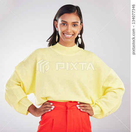 Happy woman, portrait smile and confidence standing isolated with hands on hips against a gray studio background. Face of stylish and confident Indian female posing and smiling in colorful fashion Happy woman, portrait smile and confidence standing isolated with hands on hips against a gray studio background. Face of stylish and confident Indian female posing and smiling in colorful fashion 134077346