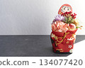 Japanese New Year decorations of Daruma and flowers on a black table in sunlight 134077420