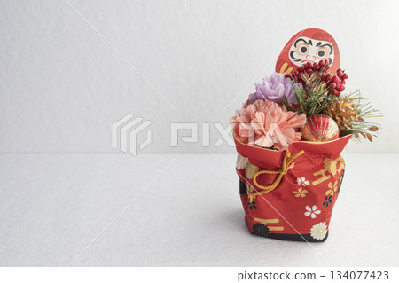 吉祥的日本新年裝飾品,達摩和鮮花在白色背景的襯托下格外醒目。 吉祥的日本新年裝飾品,達摩和鮮花在白色背景的襯托下格外醒目。 134077423