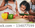 Family, cutting vegetables and cooking together, learning chef skill with parents and child in kitchen. Nutrition, healthy food and organic with people teaching and learn to cook at home with bonding 134077599