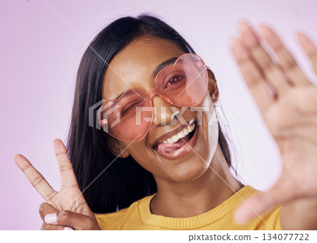 Selfie, peace and indian woman in studio with heart sunglasses, cheerful or fun on purple background. Portrait, v sign and girl gen z style fashion influencer smile for profile picture or blog post 134077722