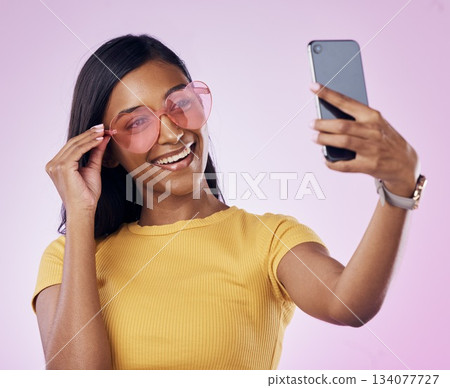 Sunglasses, selfie and happy Indian woman on pink background with cosmetics, confidence and beauty. Fashion, summer style and girl in studio take picture for social media, post and influencer blog Sunglasses, selfie and happy Indian woman on pink background with cosmetics, confidence and beauty. Fashion, summer style and girl in studio take picture for social media, post and influencer blog 134077727