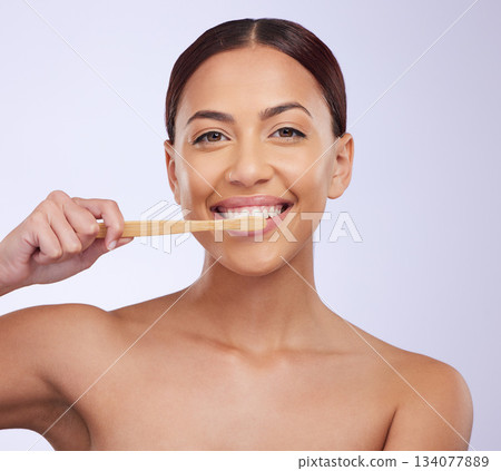 Portrait, dental or happy girl brushing teeth with smile for healthy oral hygiene in studio white background. Beauty or Brazilian woman model cleaning mouth with a natural bamboo wooden toothbrush 134077889