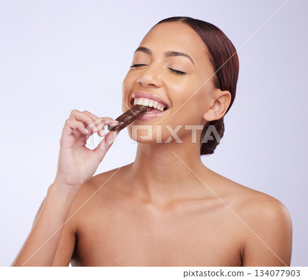 Woman, skincare and studio for eating chocolate with self care, diet or beauty with organic benefits for glow on face. Girl, model and happy for candy with wellness, health or nutrition by background Woman, skincare and studio for eating chocolate with self care, diet or beauty with organic benefits for glow on face. Girl, model and happy for candy with wellness, health or nutrition by background 134077903