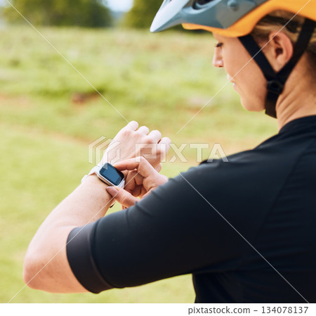 Smartwatch, heart rate and woman cyclist outdoor checking pulse for bike and cycling fitness. Exercise, wellness app and female athlete doing a time check for bicycle race in nature by grass Smartwatch, heart rate and woman cyclist outdoor checking pulse for bike and cycling fitness. Exercise, wellness app and female athlete doing a time check for bicycle race in nature by grass 134078137