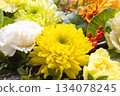 Close-up of white and yellow chrysanthemums with vibrant red berries and leaves of peony 134078245