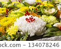 A red, green, and yellow flower water basin with a large white chrysanthemum as the main feature 134078246