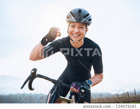 Fitness, celebration and portrait of woman cycling with power fist, success or victory in the countryside. Happy, sports and face of lady cyclist celebrating workout achievement, milestone or winning 134078261