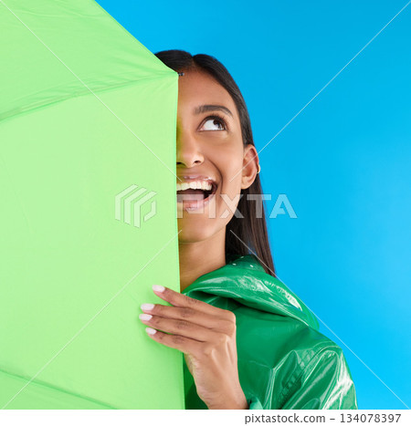 Umbrella, fun or happy woman in playful studio with raincoat, silly or happiness mockup. Goofy, face or excited female on isolated blue background or looking with smile, curious or thinking expresion 134078397