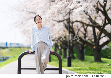 一位年輕女子在一排櫻花樹下擺姿勢。生活方式圖片 一位年輕女子在一排櫻花樹下擺姿勢。生活方式圖片 134078413