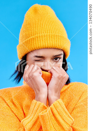 Portrait of woman in winter fashion with cozy jersey, beanie and wink isolated on blue background. Style, happiness and gen z girl in studio backdrop with mock up and warm clothing for cold weather. Portrait of woman in winter fashion with cozy jersey, beanie and wink isolated on blue background. Style, happiness and gen z girl in studio backdrop with mock up and warm clothing for cold weather. 134078490