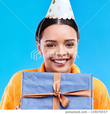 Woman, birthday and box in studio portrait with smile, happiness and present by blue background. Girl, model and party with gift, hat and excited face for celebration, event and package by backdrop 134078557