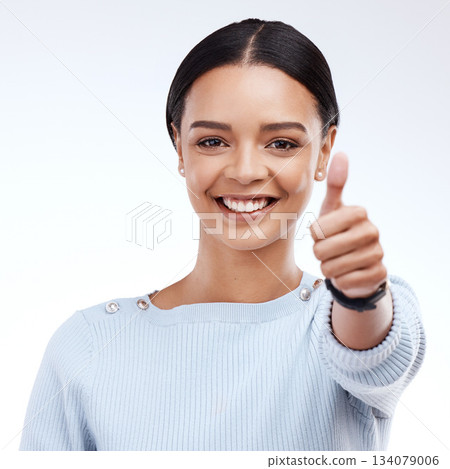 Portrait, thumbs up and motivation with a woman on a white background in studio for feedback or success. Winner, emoji or hand gesture with an attractive young female saying thank you to show support 134079006