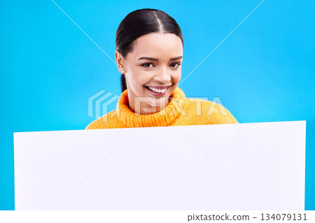 Happy, mockup and poster with portrait of woman in studio for idea, branding and announcement. Promotion, space and smile with female and sign on blue background for news, logo and advertising Happy, mockup and poster with portrait of woman in studio for idea, branding and announcement. Promotion, space and smile with female and sign on blue background for news, logo and advertising 134079131