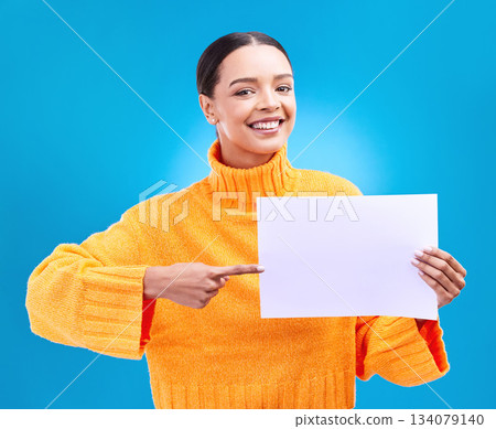 Poster, point and portrait of woman on blue background for announcement, news and information. Advertising, mockup studio and isolated happy girl with paper sign for brand, logo and product placement Poster, point and portrait of woman on blue background for announcement, news and information. Advertising, mockup studio and isolated happy girl with paper sign for brand, logo and product placement 134079140