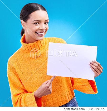 Pointing, mockup and poster with portrait of woman in studio for idea, branding and announcement. Promotion, space and smile with female and sign on blue background for news, logo and advertising 134079144