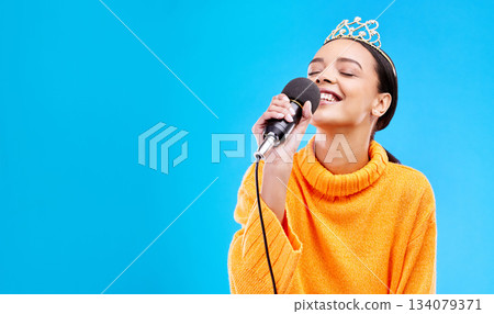 Singer woman, crown and microphone in studio mockup with smile for singing performance by blue background. Happy gen z girl, model or recording artist mic for karaoke, music and mock up with tiara Singer woman, crown and microphone in studio mockup with smile for singing performance by blue background. Happy gen z girl, model or recording artist mic for karaoke, music and mock up with tiara 134079371