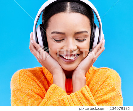 Headphones, happy music and woman in studio, blue background and backdrop. Smile, female model and listening to radio, streaming album and excited audio connection, sound and subscription to podcast 134079385