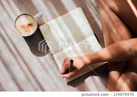 Notebook, writing and woman hands with coffee for ideas, inspiration and creativity on floor above in sunshine. Creative person with latte for mindfulness, healing notes or self care goals of writer Notebook, writing and woman hands with coffee for ideas, inspiration and creativity on floor above in sunshine. Creative person with latte for mindfulness, healing notes or self care goals of writer 134079470