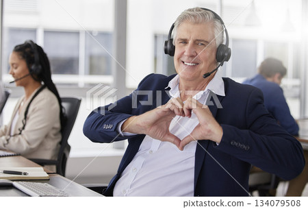 Portrait, heart hands or mature happy man in call center with smile excited about customer care services in office. Sales, communication or friendly senior consultant with love sign at crm business 134079508