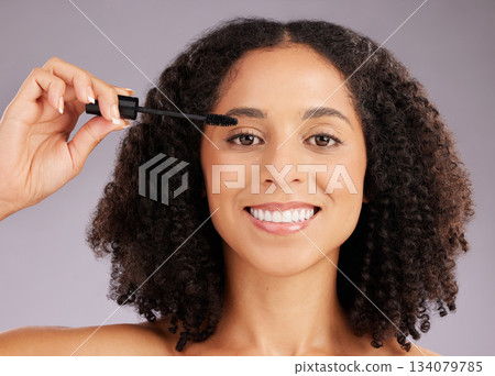 Happy woman, face and smile in portrait with mascara, beauty and makeup with cosmetic product on studio background. Female, cosmetology and eyelash extension with brush, happiness and cosmetics glow Happy woman, face and smile in portrait with mascara, beauty and makeup with cosmetic product on studio background. Female, cosmetology and eyelash extension with brush, happiness and cosmetics glow 134079785