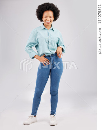 Fashion, casual and young black woman in a studio with a stylish and trendy outfit with a jeans and shirt. Happy, smile and portrait of an African female model with style isolated by gray background. 134079861