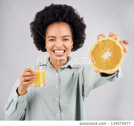 Portrait, orange and juice with a woman, happy in studio on a gray background for health or vitamin c. Face, drink and fruit with a young female drinking a fresh beverage in a glass for nutrition 134079877