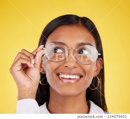 Happy, smile and woman with glasses in a studio for optical health, wellness and awareness. Happiness, optometry and Indian female model with spectacles for eye care isolated by a yellow background. Happy, smile and woman with glasses in a studio for optical health, wellness and awareness. Happiness, optometry and Indian female model with spectacles for eye care isolated by a yellow background. 134079932