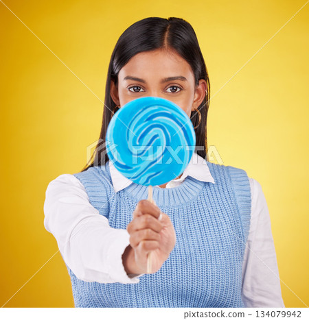 Hide, lollipop and candy with portrait of woman in studio for sweets, snack and food. Treats, dessert and sugar confectionery with female isolated on yellow background for diet, eating and cover Hide, lollipop and candy with portrait of woman in studio for sweets, snack and food. Treats, dessert and sugar confectionery with female isolated on yellow background for diet, eating and cover 134079942