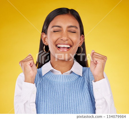 Celebration, winner and fist pump with woman in studio for success, excited and happy cheering. Wow, yes and achievement with female on yellow background for victory, promotion and good news 134079984