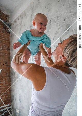 Moscow, Russia, 29.06.23. A woman is holding a baby in a blue outfit 134080031