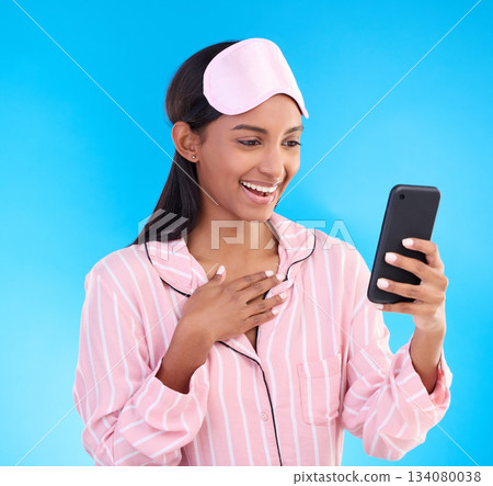 Wow, phone and pajamas with a woman on a blue background in studio browsing social media in the morning. Mobile, contact and gossip with an attractive young female reading good news while texting Wow, phone and pajamas with a woman on a blue background in studio browsing social media in the morning. Mobile, contact and gossip with an attractive young female reading good news while texting 134080038