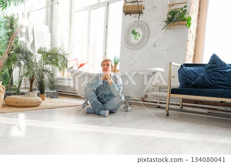 Moscow, Russia, 29.06.23. A man sits in a bathtub in a room with plants and a white wall Moscow, Russia, 29.06.23. A man sits in a bathtub in a room with plants and a white wall 134080041