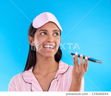Woman in pajamas, smartphone and phone call on speaker, conversation and smile against a blue studio background. Female, cellphone and girl in sleepwear, chatting and communication with joy and plans 134080044