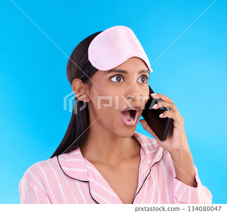 Phone call, shock and woman in pajamas in a studio with shocking, winning or good news. Surprise, happy and Indian female model on a mobile conversation with a wtf, omg or wow face by blue background 134080047