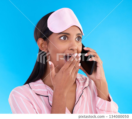 Phone call, surprise and female in pyjamas in studio with shocking, winning or good news. Communication, shock and woman model having gossip conversation with wtf, omg or wow face by blue background. Phone call, surprise and female in pyjamas in studio with shocking, winning or good news. Communication, shock and woman model having gossip conversation with wtf, omg or wow face by blue background. 134080050