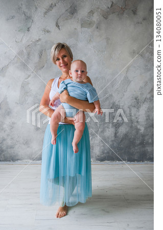 Moscow, Russia, 29.06.23. A woman is holding a baby in a blue shirt Moscow, Russia, 29.06.23. A woman is holding a baby in a blue shirt 134080051