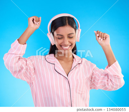 Happy, dance and woman in pajamas, headphones and cheerful on a blue studio background. Female, joyful and lady with headset, waking up and dancing with sounds, streaming music and songs for movement Happy, dance and woman in pajamas, headphones and cheerful on a blue studio background. Female, joyful and lady with headset, waking up and dancing with sounds, streaming music and songs for movement 134080055